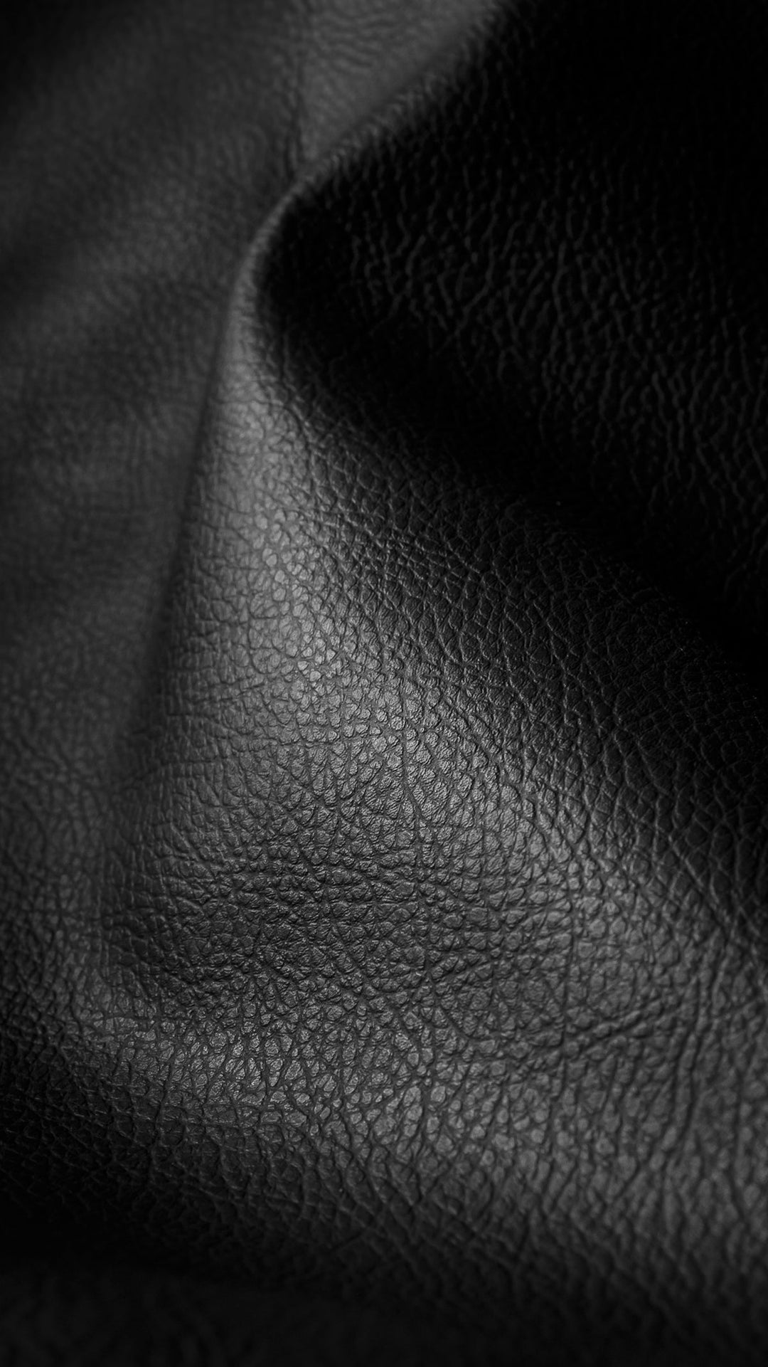 Close-up of black leather with a textured surface and soft folds